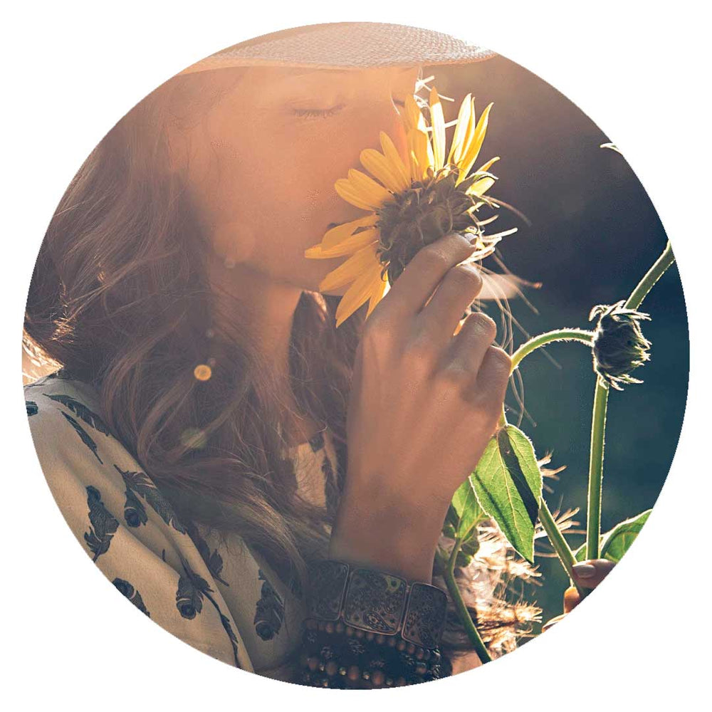 Picture of a woman smelling a sunflower- Amazonian SkinFood Fragrance Transparency