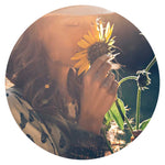 Picture of a woman smelling a sunflower- Amazonian SkinFood Fragrance Transparency